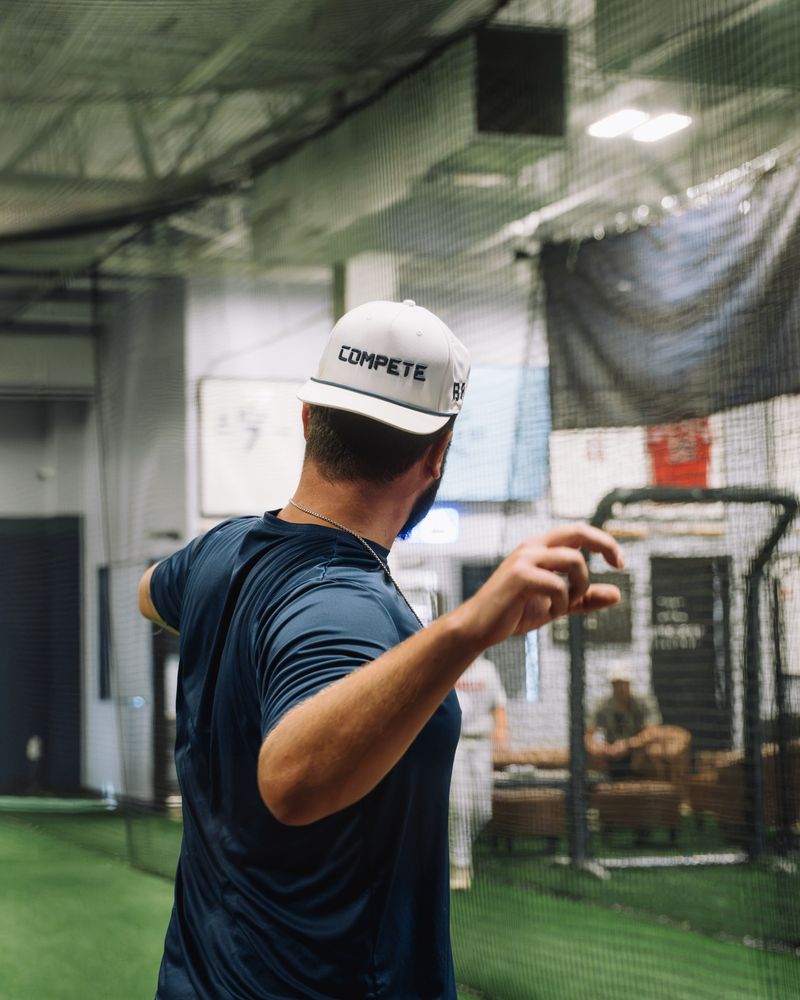 Compete BP coach in a Compete cap throwing in the cage