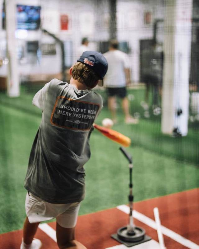 Teen hitter finishing his swing in the cage